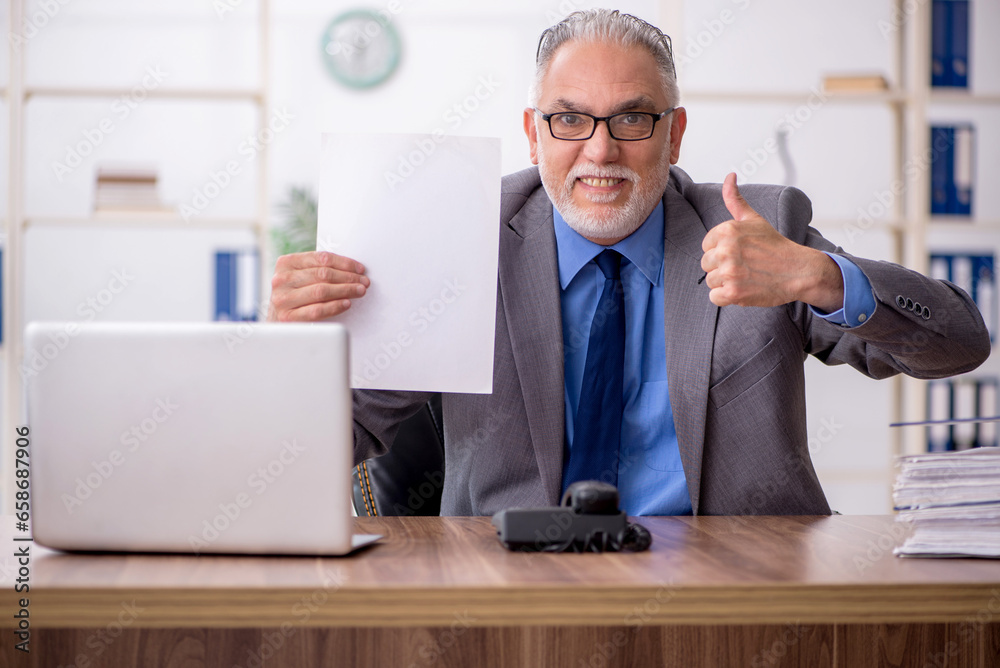 Old male employee working in the office Old male employee working in the office