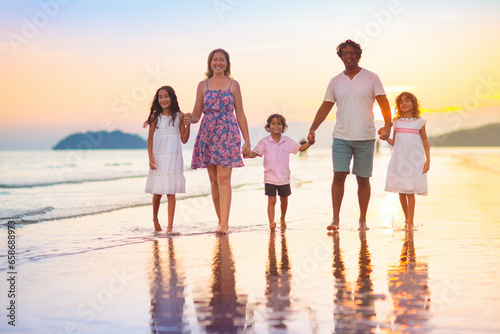 Family walking on tropical beach at sunset