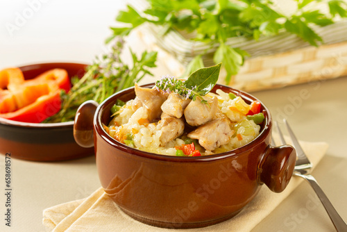 Cooked rice with vegetables and rabbit meat in a clay pot on the table. horizontal