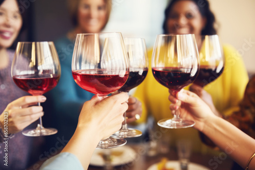 Group of friends toasting with red wine glasses at a festive lunch party