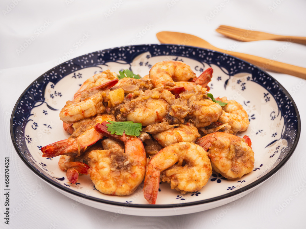 Stir fried shrimps with garlic and white pepper in plate on white fabric background. Thai Food