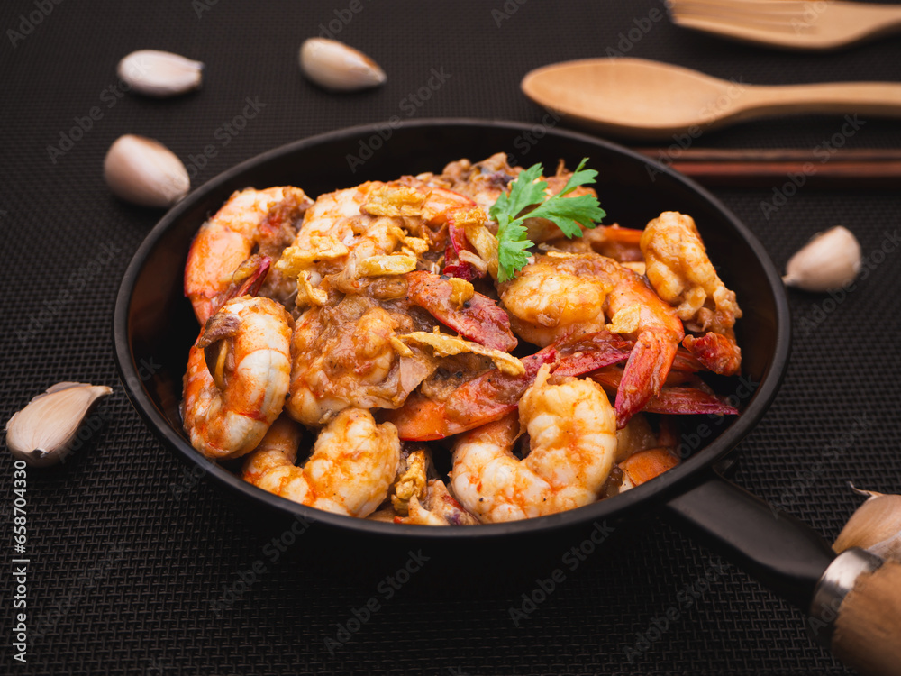 Stir fried shrimps with garlic and white pepper in pan on black place mat. Thai Food