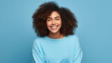 Cheerful Afro beautiful woman Smiling cute girl with long hair in colorful cloth has pleasant smile, discusses amazing promo over isolated blue background, Generative AI