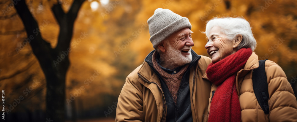 Fototapeta premium Smiling senior couple spends time in the park in autumn