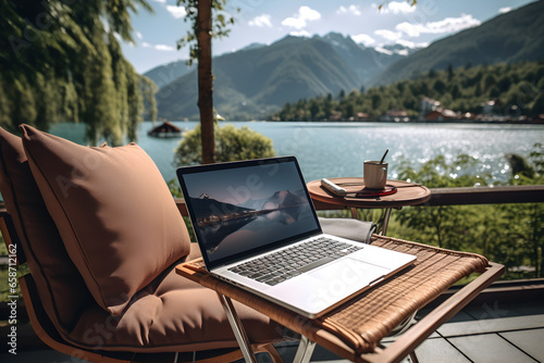 Laptop computer on a terrace with beautiful lake view background, Digital nomad’s lifestyle,  Remote job and teleworking concept, Vacation Leave, Nomad visa photo