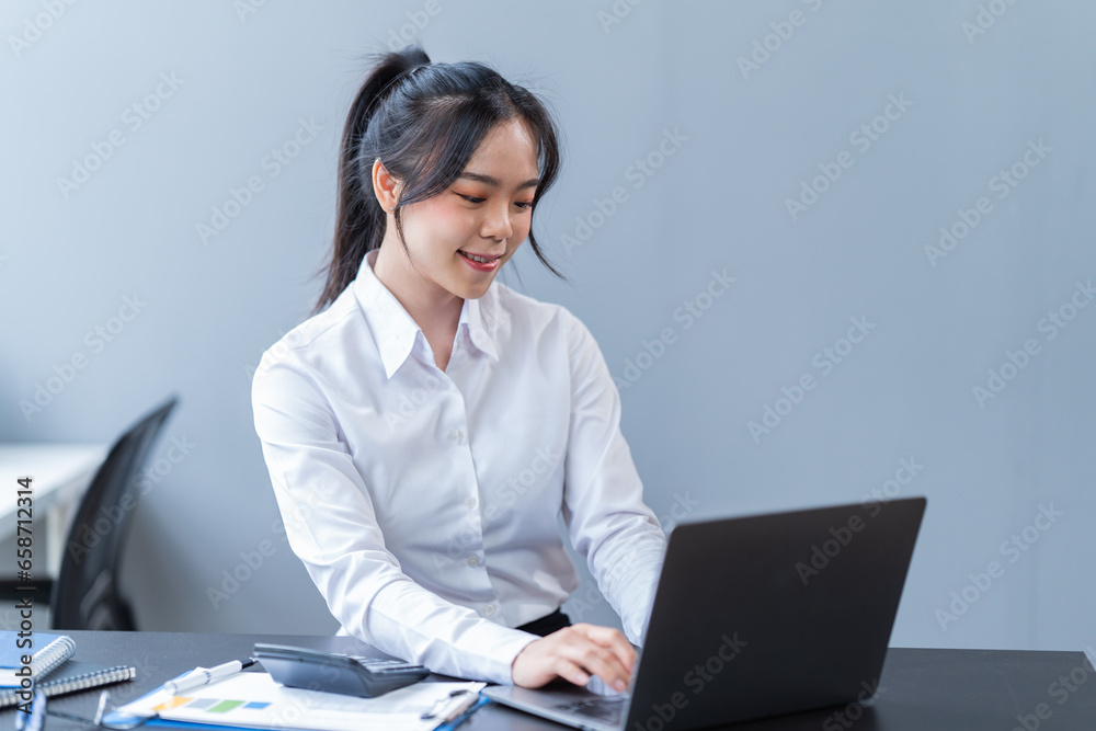 Portrait of a happy beautiful Asian businesswoman. Working with a laptop and Mobilphone in a company office Portrait of a happy beautiful Asian businesswoman. Working with a laptop and Mobilphone in a company office