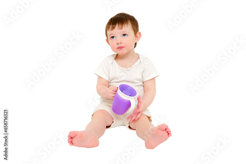 Happy baby drinks water from cup on studio, isolated on white background. Resting child with cup juice in hands, isolated on white background. Kid about two years old (one year nine months) © Андрей Журавлев