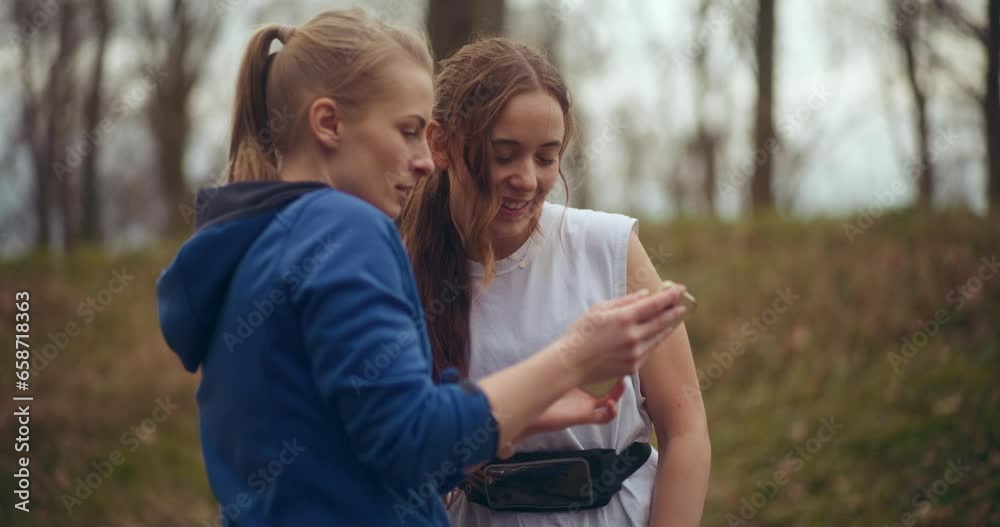 Woman sharing mobile phone with smiling female friend Woman sharing mobile phone with smiling female friend