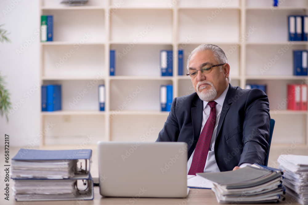 Old male employee sitting at workplace Old male employee sitting at workplace