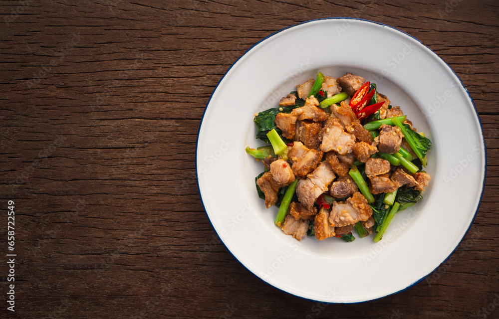 Top view of stir fried crispy pork with kale and oyster sauce in plate on wooden table. Asia Food Top view of stir fried crispy pork with kale and oyster sauce in plate on wooden table. Asia Food