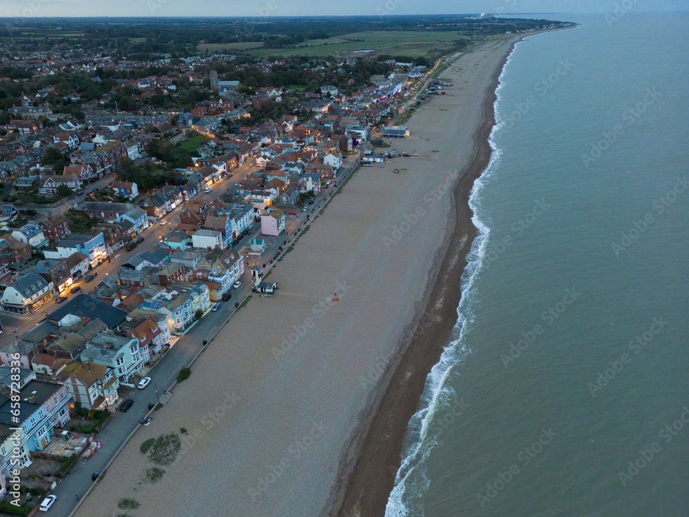 Dramatic aerial view of a dusk view of the popular Suffolk coastal town of Aldeburgh. Showing the orange street lights and lit dwellings.
