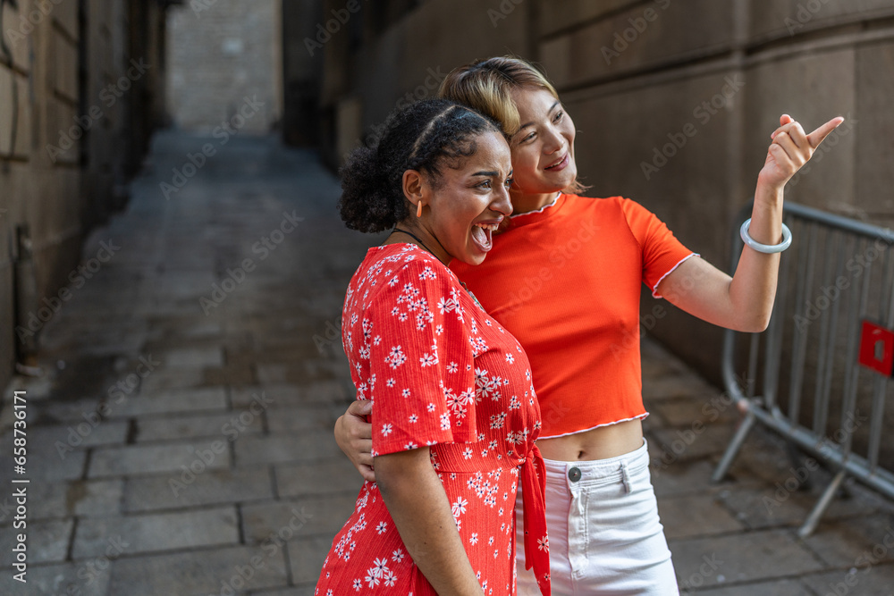Multi-ethnic lesbian tourists pointing to a side in the street Multi-ethnic lesbian tourists pointing to a side in the street