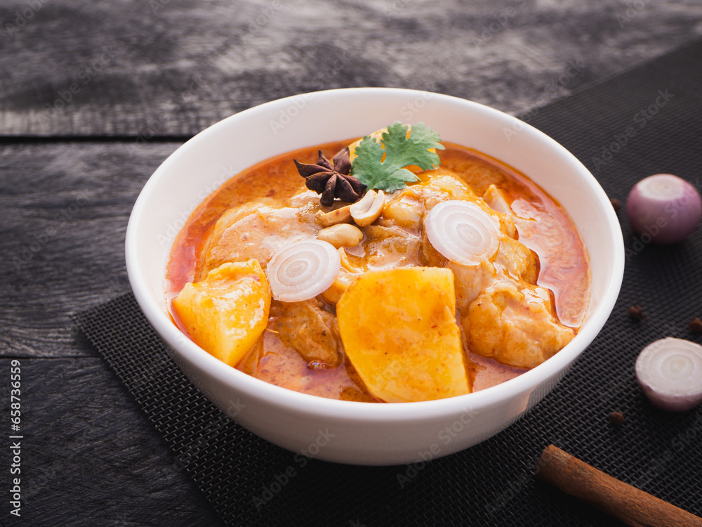 Massaman curry with chicken and potatoes in bowl on wooden background. Thai Food Massaman curry with chicken and potatoes in bowl on wooden background. Thai Food