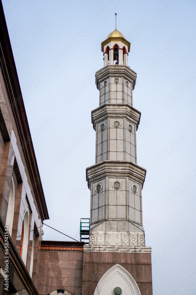 Fototapeta premium The mosque building with a golden yellow dome appears under a clear sky. the tower is inscribed in Aran language.
