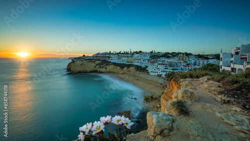 View of Carvoeiro fishing village with beautiful beach, Algarve, Portugal. View of beach in Carvoeiro town with small houses on coast of Portugal at sunset (long exposure)