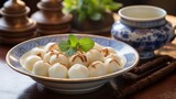 Thai dessert: Bua Loi, also known as Bua Loy, are sticky rice balls cooked in a creamy coconut milk syrup and served in a white porcelain bowl on a wooden table alongside an afternoon tea set.