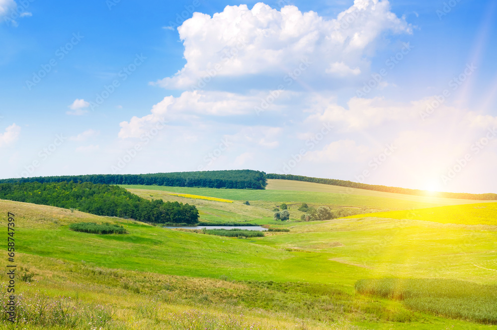 Fototapeta premium Green meadow on a hilly landscape and Sky with bright sunise.