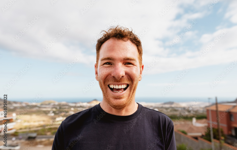 Happy Caucasian young man smiling in front of camera at house rooftop Happy Caucasian young man smiling in front of camera at house rooftop
