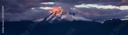 Mountain Peak Covered in clouds and snow. Dramatic Sunset Sky. Aerial Nature Background.