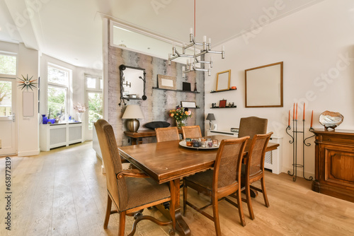 a dining room with wood flooring and white walls there is a large wooden table surrounded by chairs in the room