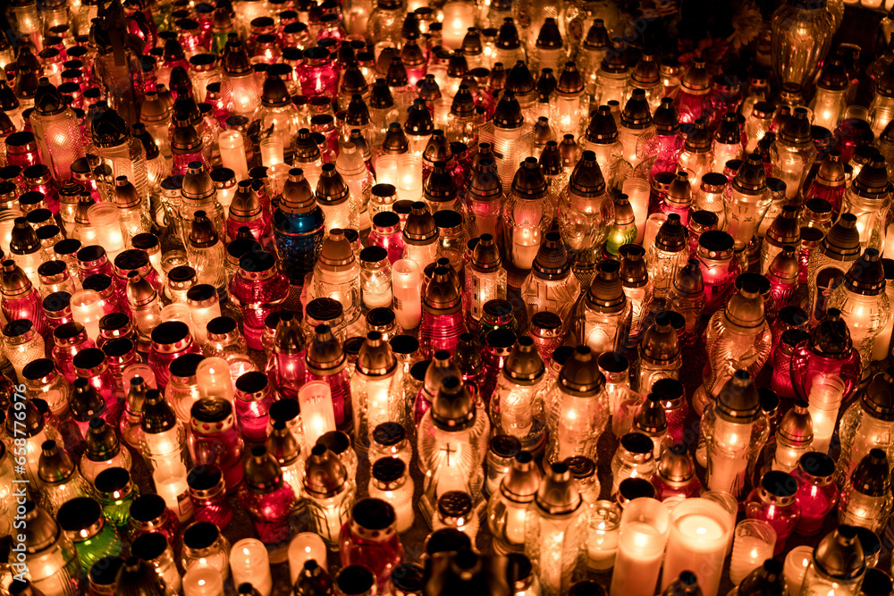 Fototapeta premium Many lit grave candles at the base of a cemetery monument — Poland, November 1, All Saints’ Day (also known as All Souls’ Day / Day of the Dead)