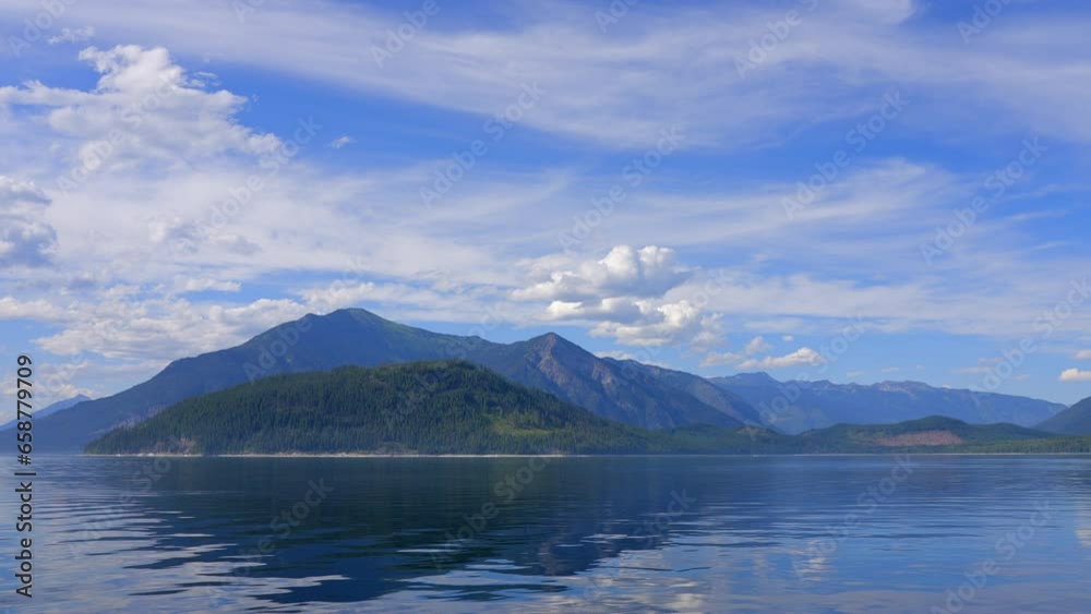 Establishing shot of Mountain lake with blue sky and white clouds in Vancouver, Canada, North America. Day time on July 2023. Still camera view. ProRes 422 HQ. Upper Arrow Lake. Establishing shot of Mountain lake with blue sky and white clouds in Vancouver, Canada, North America. Day time on July 2023. Still camera view. ProRes 422 HQ. Upper Arrow Lake.
