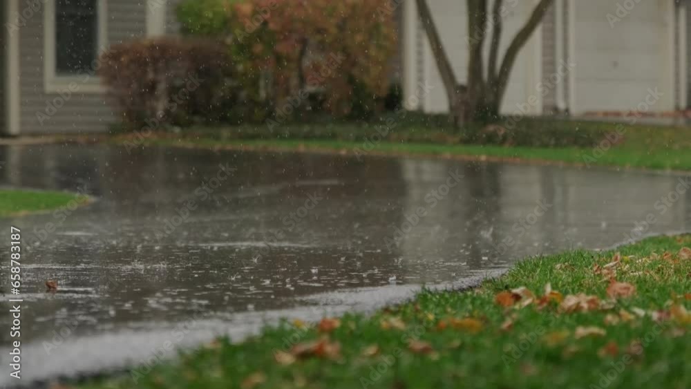 Slow Motion footage, heavy rain water drops falling into big puddle on asphalt, flooding the street.