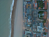Drone top down view of a dusk view of a British coastal town. The beach can be seen on the left, at high tide.