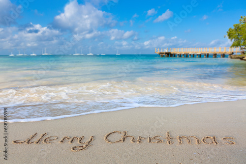 Merry christmas handwriting in the white caribbean sand .