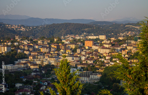 Sochi, Krasnodar Krai, Russia - August, 7, 2023: panoramic view of residential buildings among green hills in the city center at sunset and space for copying