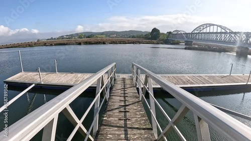 wooden pier on the Coura River with a view of the railway Bridge in Caminha, Alto Minho Subregion, district of Viana do Castelo, Portugal photo