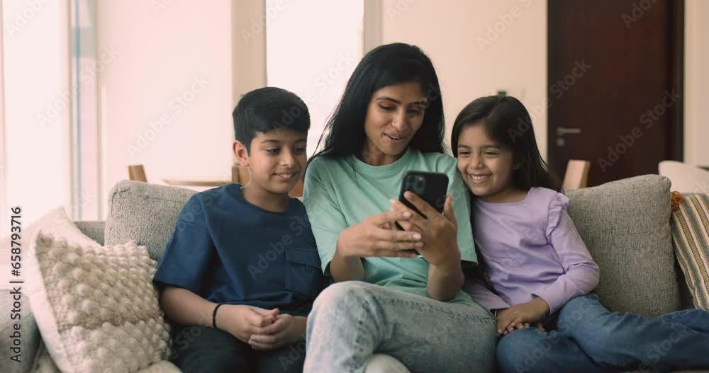 Beautiful young Indian woman and children having fun spend time together on internet using smartphone, enjoy on-line videos or new mobile filter application on weekday at home. Modern technologies Beautiful young Indian woman and children having fun spend time together on internet using smartphone, enjoy on-line videos or new mobile filter application on weekday at home. Modern technologies