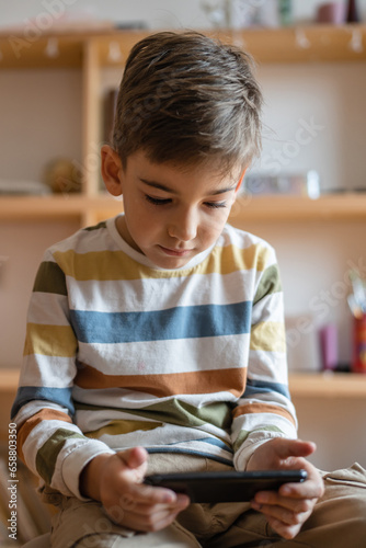 One caucasian boy child use smartphone mobile phone at home play games