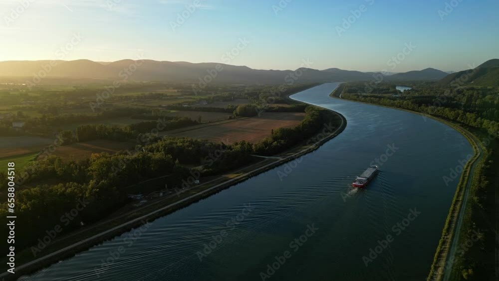 Panoramic view of the Rhone river bed in southern France with a passing passenger ship during sunrise on an autumn morning. Panoramic view of the Rhone river bed in southern France with a passing passenger ship during sunrise on an autumn morning.