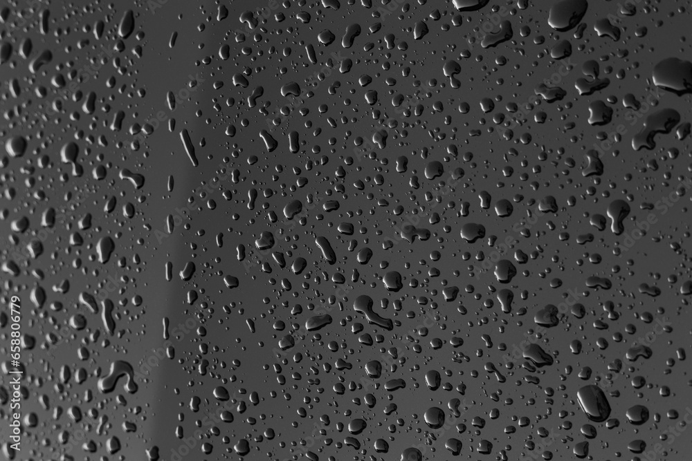 Rain or water drops different size on a black shiny car hood surface. Water droplets on dark iron surface and texture. Abstract background and water texture for design. Rain or water drops different size on a black shiny car hood surface. Water droplets on dark iron surface and texture. Abstract background and water texture for design.