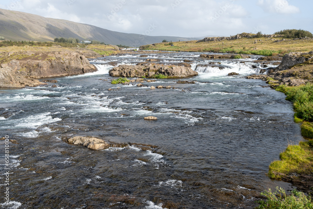 Fototapeta premium River with many picturesque cascades on Route 47 near Reykjavik, Iceland under sunny autumn cloudscape.