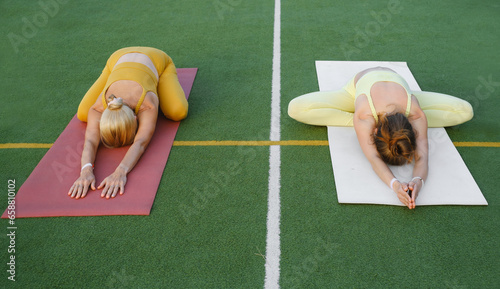 Two woman doing yoga outdoors Mother and adult daughter practicing together. Mature female and young girl having mindfulness activities. Family Active lifestyle, training in mountains photo