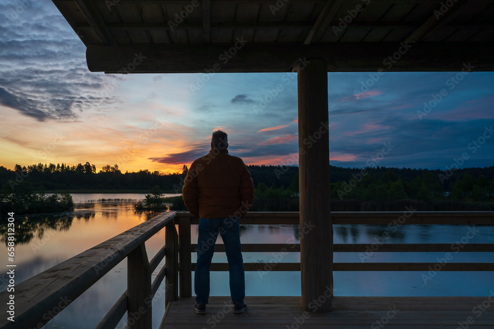 Fototapeta premium Man looking at the lake and the sunrise
