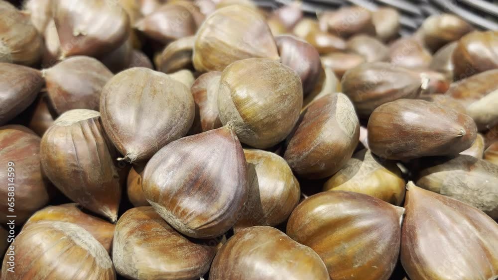 Close-up of edible chestnuts in a supermarket basket. Dark and light brown colored. Food. Selective focus Camera slowly moving backwards. Close-up of edible chestnuts in a supermarket basket. Dark and light brown colored. Food. Selective focus Camera slowly moving backwards.