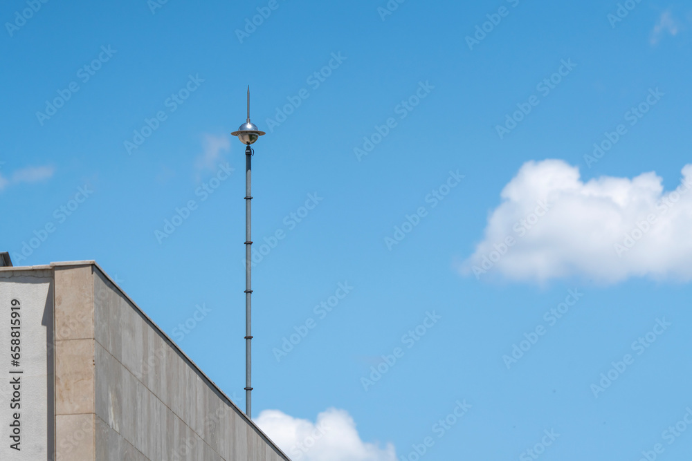 Lightning rod on the roof of a building against a blue sky. Lightning strike Lightning rod on the roof of a building against a blue sky. Lightning strike