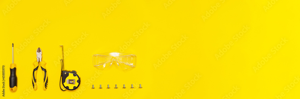 Set of tools, screwdriver, cutting pliers, tape measure, protective glasses and screws on yellow background, banner, flat lay. - obrazy, fototapety, plakaty 