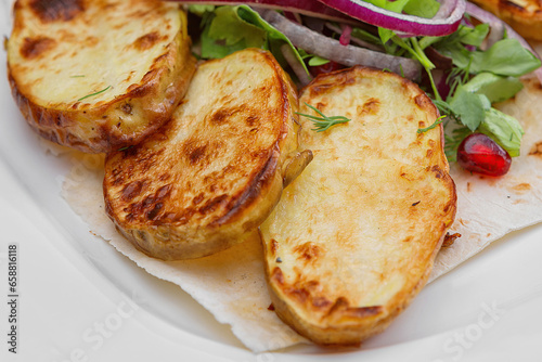 Baked potatoes with onions and herbs, close-up