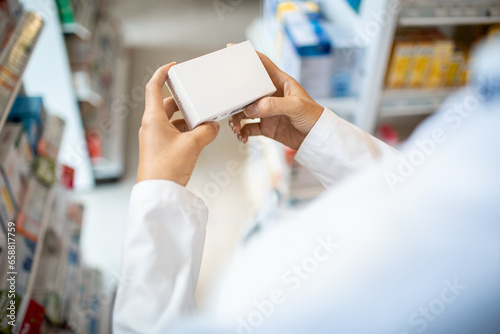 Close up of a pharmacist holding medication with a blank box at the pharmacy photo
