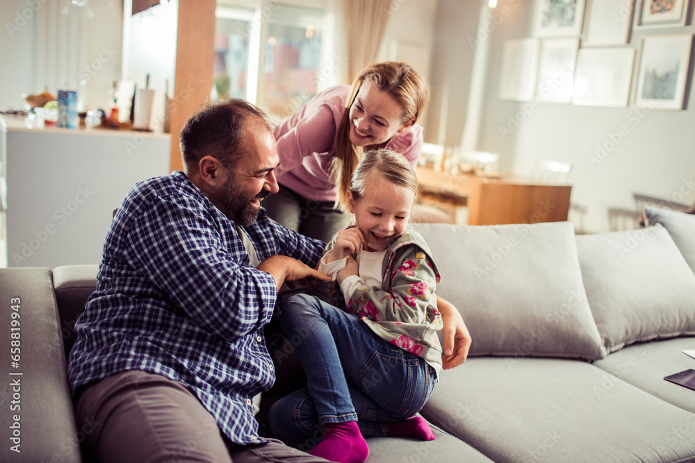 Young Caucasian family playing and having fun on the couch at home Young Caucasian family playing and having fun on the couch at home