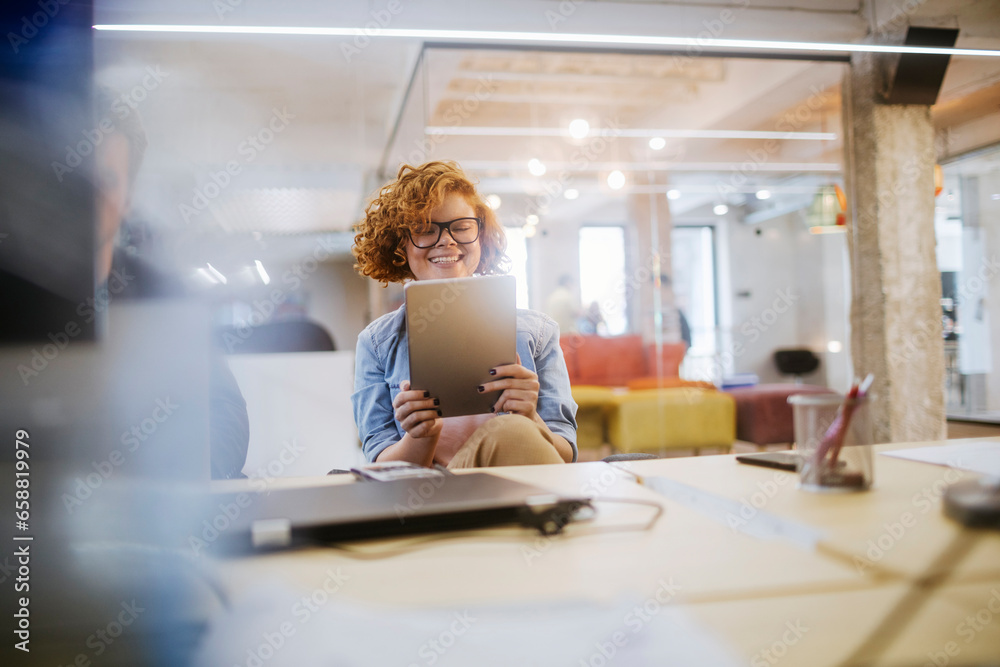 Young Caucasian woman using a tablet in the office of a startup company Young Caucasian woman using a tablet in the office of a startup company