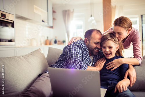 Young Caucasian family having fun and using a laptop at home