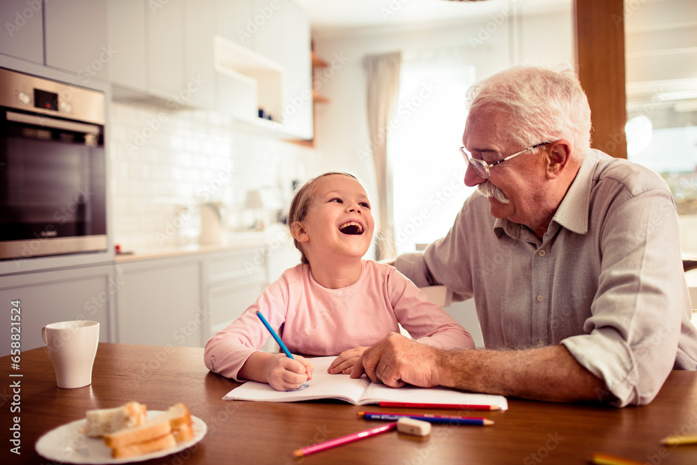 Young girl doing homework with the help of her grandfather at home Young girl doing homework with the help of her grandfather at home