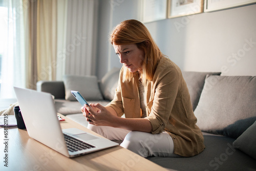 Stressed young woman going over bills and payments on the couch at home