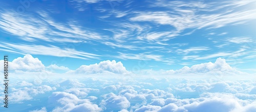 Fototapeta Naklejka Na Ścianę i Meble -  Pale blue sky with clouds and a plane contrail displaying a gradient of color and illumination above the horizon With copyspace for text