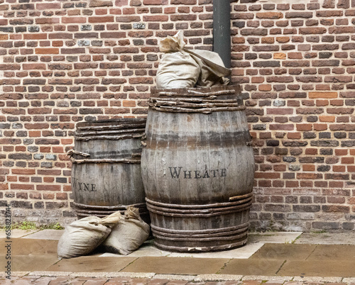 Dos viejos barriles de madera, una pared de ladrillo y unos sacos  de contenido desconocido